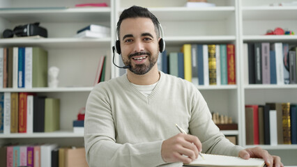 Sticker - Young hispanic man student having video call writing on notebook at library university