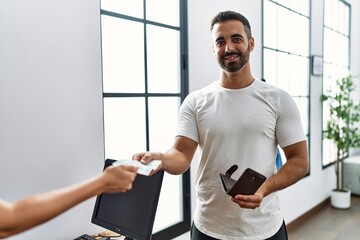 Sticker - Young hispanic man customer paying purchase using credit card at clothing store