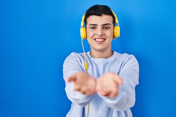 Canvas Print - Non binary person listening to music using headphones smiling with hands palms together receiving or giving gesture. hold and protection