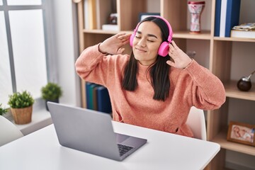 Poster - Young hispanic woman listening to music sitting on table at home