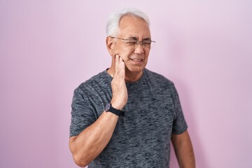 Wall Mural - Middle age man with grey hair standing over pink background touching mouth with hand with painful expression because of toothache or dental illness on teeth. dentist