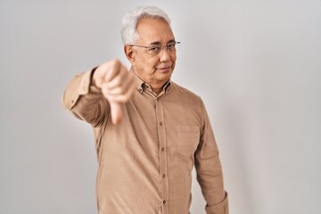 Canvas Print - Hispanic senior man wearing glasses looking unhappy and angry showing rejection and negative with thumbs down gesture. bad expression.