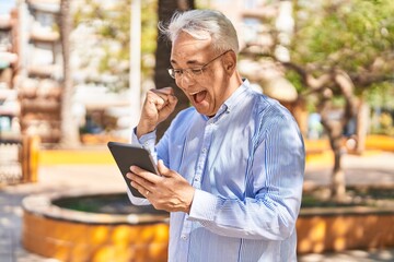 Poster - Senior man smiling confident using touchpad at park