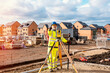 © Iryna - Surveyor builder site engineer with theodolite total station at construction site outdoors during surveying work