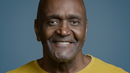 Male portrait mature african american man looking camera smiling with white toothy smile joyful ethnic senior male athlete satisfied client happy with service laughing posing in blue background studio