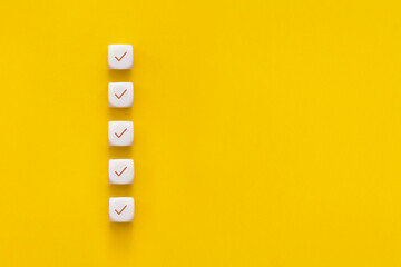 сubes with check mark on yellow background, checklist concept with copy space.
