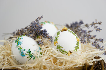 easter holiday in a nest white eggs with a pattern embroidery ribbons on eggshell lavender flowers decoration close-up easter holiday succeeded shavings for packaging embroidery ribbons on eggshells