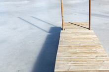 A Wooden Pier And Shadow Over White, Frozen Water 