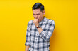 © Bangun Stock Photo - Sick young handsome Asian man 20s wearing a plaid shirt coughing covering mouth with hand keeping eyes closed isolated on yellow background. People lifestyle concept