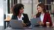 © Parichat - African American businesswoman and Asian businesswoman working together as a team to get their project done.