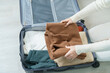 Woman hand packing her winter clothes in luggage. Time to travel, trip, Relax, spring or autumn or winter season and vacation concepts