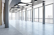 © Who is Danny - Perspective view on panoramic window with city view background in modern business center hall with illuminated round lamps and metallic pillars on concrete floor. 3D rendering