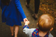 © Cavan Images - A little girl holds her small brother's hand and leads him on a path
