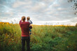 © Cavan Images - A father holds his small son in his arms in a field at sunset