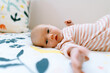 © Cavan Images - Closeup portrait of a baby girl laying on a colorful comforter