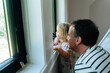 © Cavan Images - Side view of a father and daughter looking at a window
