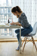 © Cavan Images - millennial girl draws fabulous images on paper while sitting at home