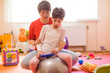 © Westend61 - Physical therapist and girl with disability sitting on fitness ball in rehabilitation centre