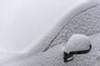 Car covered with snow. Car mirror sticking out of the snow.
