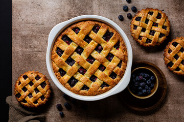 Poster - Brawn table with homemade bakery. Whole baked mixed berry crust pie or tart with lattice, mini tarts. Fresh berries. Top view.