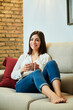 © Cavan - Young woman relaxing on the couch at home.