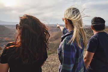 Three people looking to the Grand Canyon from a viewpoint, windy