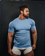 © Serge Lee - Bearded muscled man in blue shirt and white boxers looking to right side. Sexy fitness guy wearing casual clothes at black background. Attractive bodybuilder in studio.