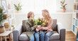 © candy1812 - Mother and daughter sitting on the sofa with tulips in their hands indoor.