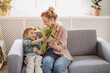 © candy1812 - Cute boy sitting on the sofa with mom and giving a bouquet of tulips to her.