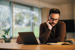 © bnenin - Male boss reading notes in a notebook, sitting in front of the laptop at the office.