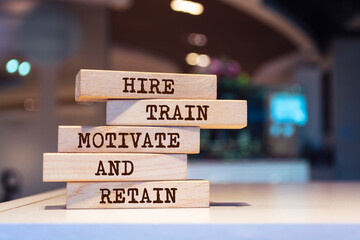 wooden blocks with words 'hire, train, motivate and retain'.