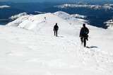 Fototapeta Na sufit - Snow hiker walking in a snowy hillside in a sunny day