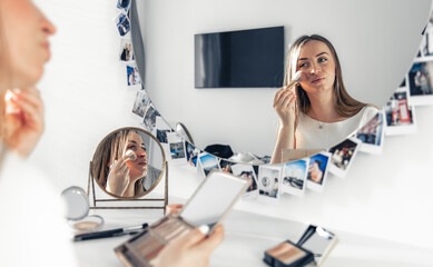 Canvas Print - A pregnant woman applies makeup at home in front of a mirror.