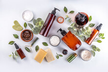 Natural Organic Skin Care Flat Lay. Natural Organic Beauty Cosmetic Products On White Background: Hand Lotion, Face Cream In Jar, Essential Oil, Skin Roller, With Eucalyptus And Tea Tree Leaves