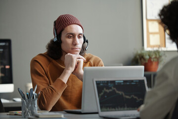 Aufkleber - Young serious male IT support operator sitting by workplace in front of laptop and looking at camera while listening to online client