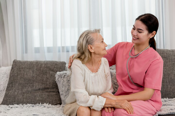 Wall Mural - Young professional confident skilled woman doctor visiting old patient lady at home for treatment control care giving. Nurse talking to Caucasian senior patient. Healthcare concept