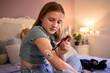 © Monkey Business - Young Diabetic Girl Sitting On Bed In Bedroom At Home Using Kit To Measure And Check Insulin Levels
