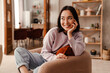© Drobot Dean - Beautiful asian woman smiling and looking away while sitting at home