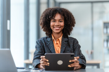 Using tablet pc, Young pretty african american business woman bookkeepers working with balance sheet yearly reports to calculate tax and online consult in modern office.