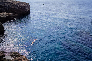 Wall Mural - Vacation. Young woman swimming and bathing at sea rock lagoon.