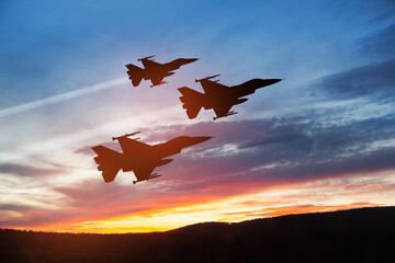 Wall Mural - Air Force Day. Aircraft silhouettes on background of sunset. Combat flight of interceptors on a mission.