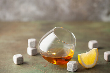 Wall Mural - Glass of whiskey with lemon and stones for cooling on dark background