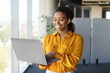 © Prostock-studio - Successful african american businesswoman with laptop in hands standing near window in office interior, copy space