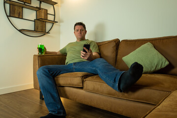 single lonely caucasian middle aged man spending St Patrick's day alone at home with green clothes and t shirt but no company so is bored searching cell phone for connections and stimulation 