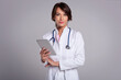 © sepy - Studio portrait of middle aged female doctor using digital tablet for work and standing at isolated background