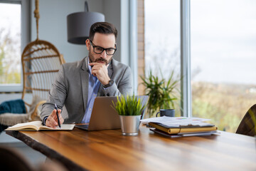 Portrait of businessman while using laptop in office, copy space