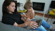 © Marco - Parent multi tasking in front of laptop computer laying on couch. Toddler baby sitting on mother lap while working from home. Cute modern parenting lifestyle