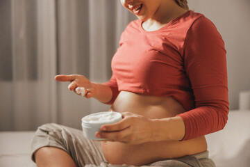 Wall Mural - Unrecognizable Pregnant Woman Applying Moisturizing Cream On Her Belly