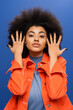 © LIGHTFIELD STUDIOS - Curly african american woman in jacket posing on blue background.
