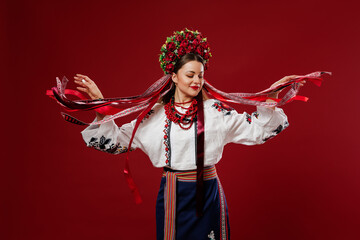 Portrait of ukrainian woman in traditional ethnic clothing and floral red wreath on viva magenta studio background. Ukrainian national embroidered dress call vyshyvanka. Pray for Ukraine